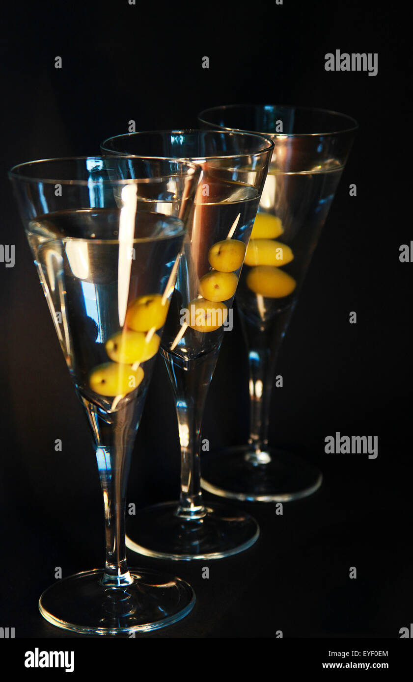 Drei Martini-Cocktails mit Oliven vor dem dunklen Hintergrund Stockfoto