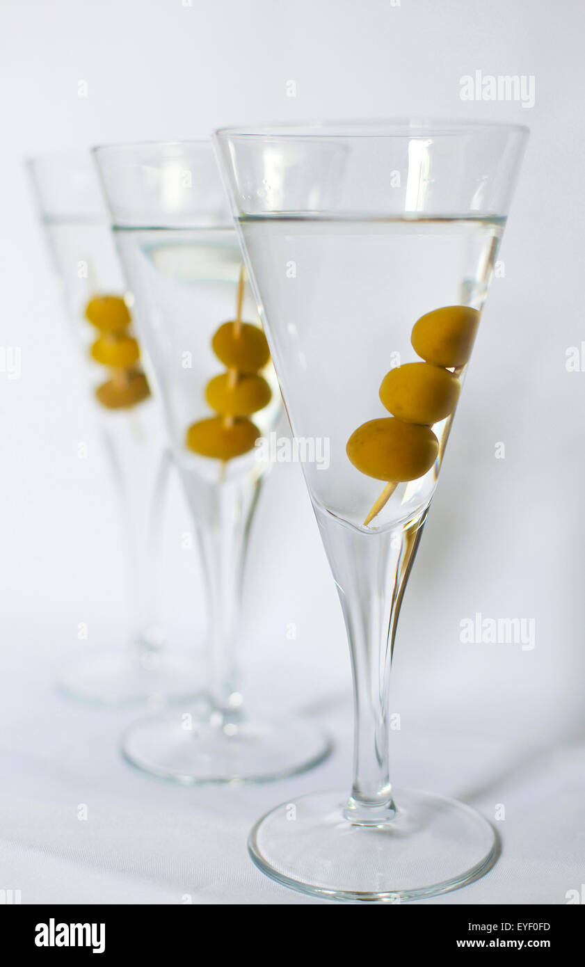 Drei Martini-Cocktails mit Oliven vor einem weißen Hintergrund Stockfoto
