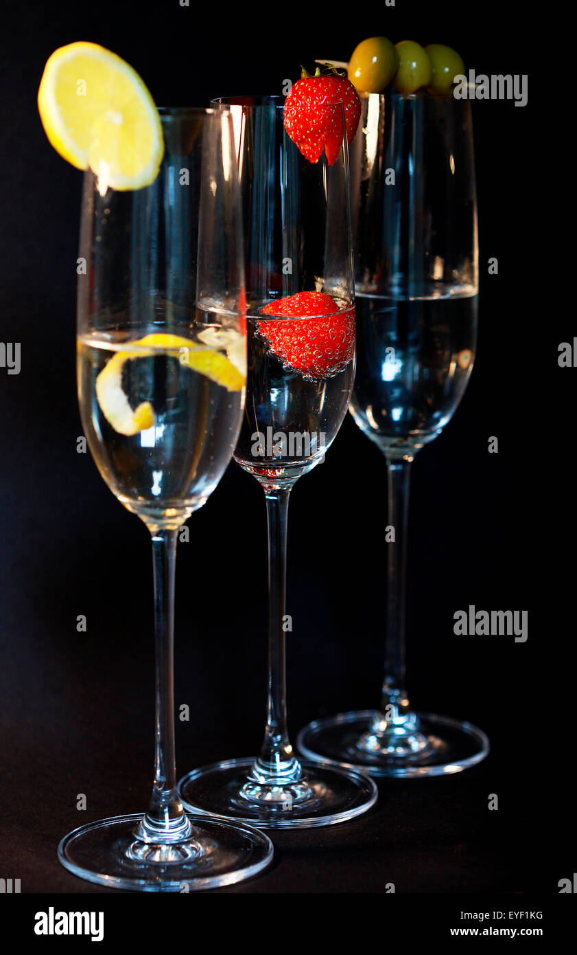 Drei verschiedene Cocktails mit Beilage vor schwarzem Hintergrund Stockfoto