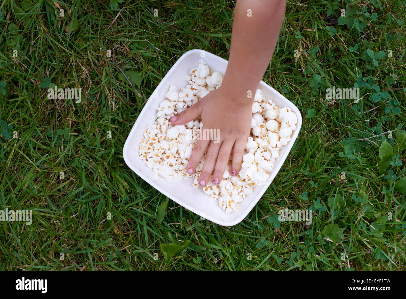 Kind blondes Mädchen essen Popcorn außerhalb Stockfoto