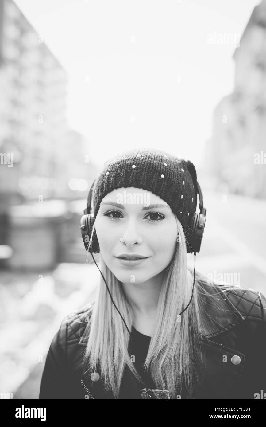 junge schöne blonde glatte Haare Frau in der Stadt mit Kopfhörern Musik hören Stockfoto