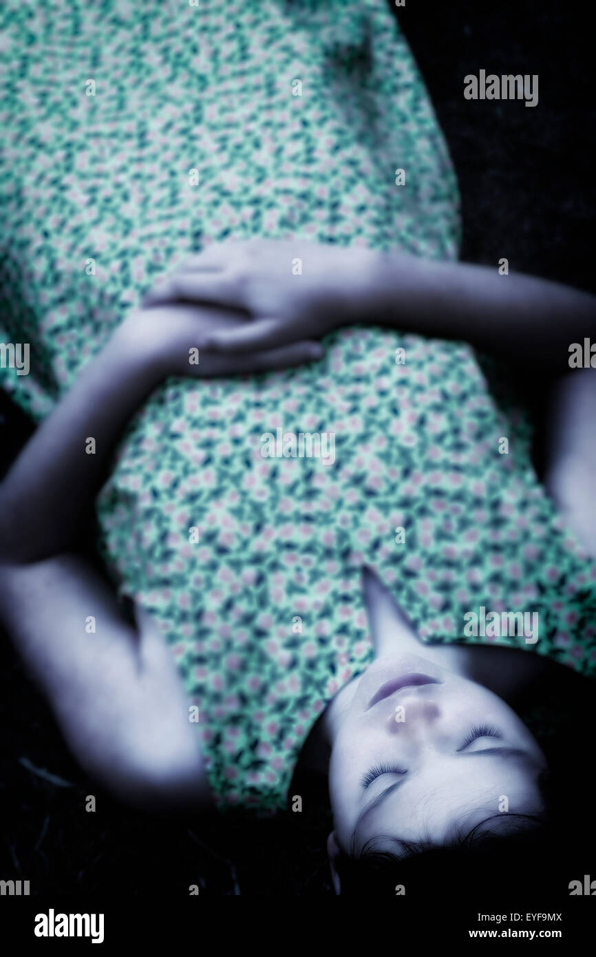 ein Mädchen mit geschlossenen Augen auf dem Boden liegend Stockfoto