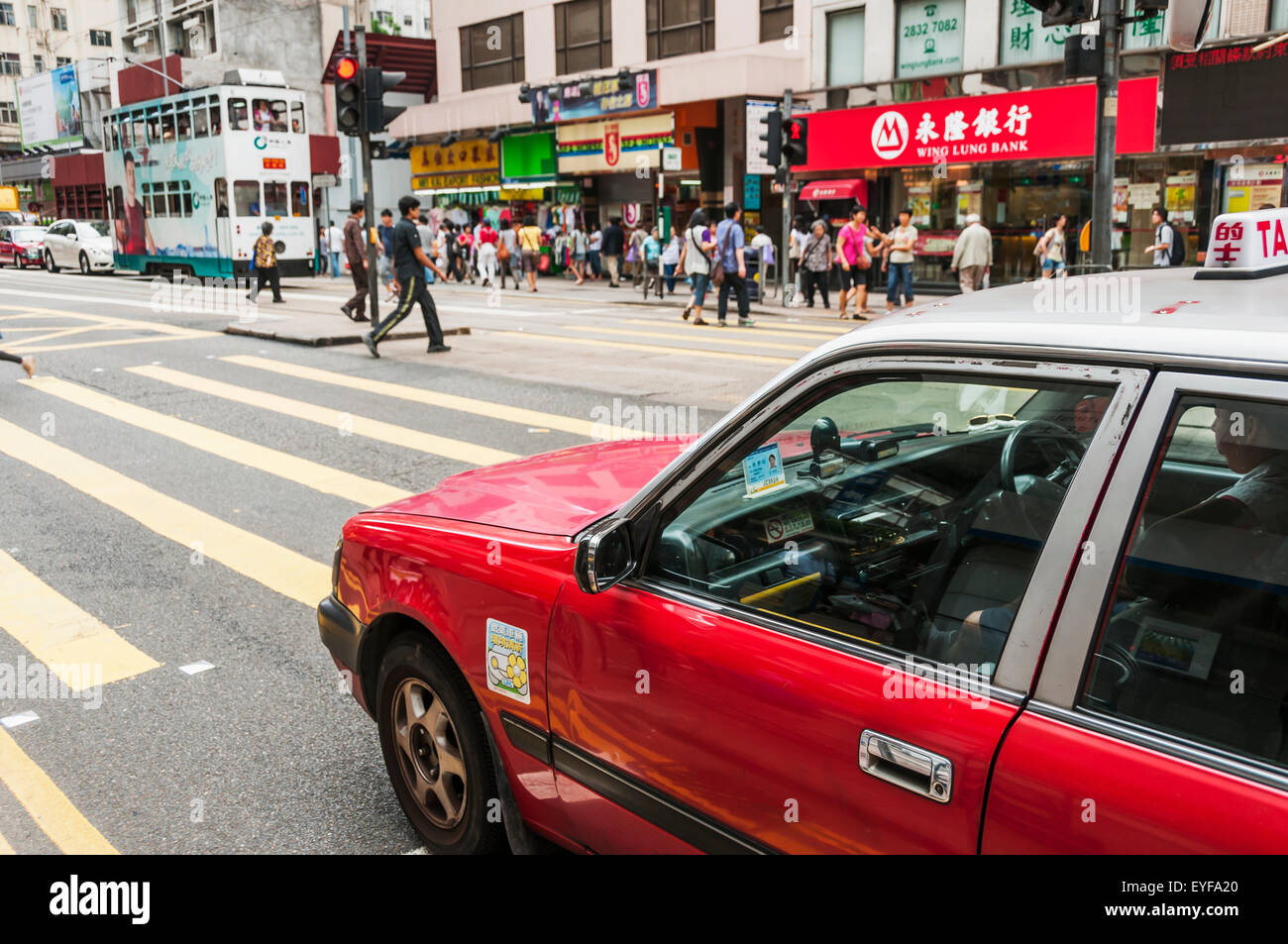 Fußgänger überqueren einer viel befahrenen Straße mit einem roten Taxi am Zebrastreifen, Central District; Hongkong, China Stockfoto