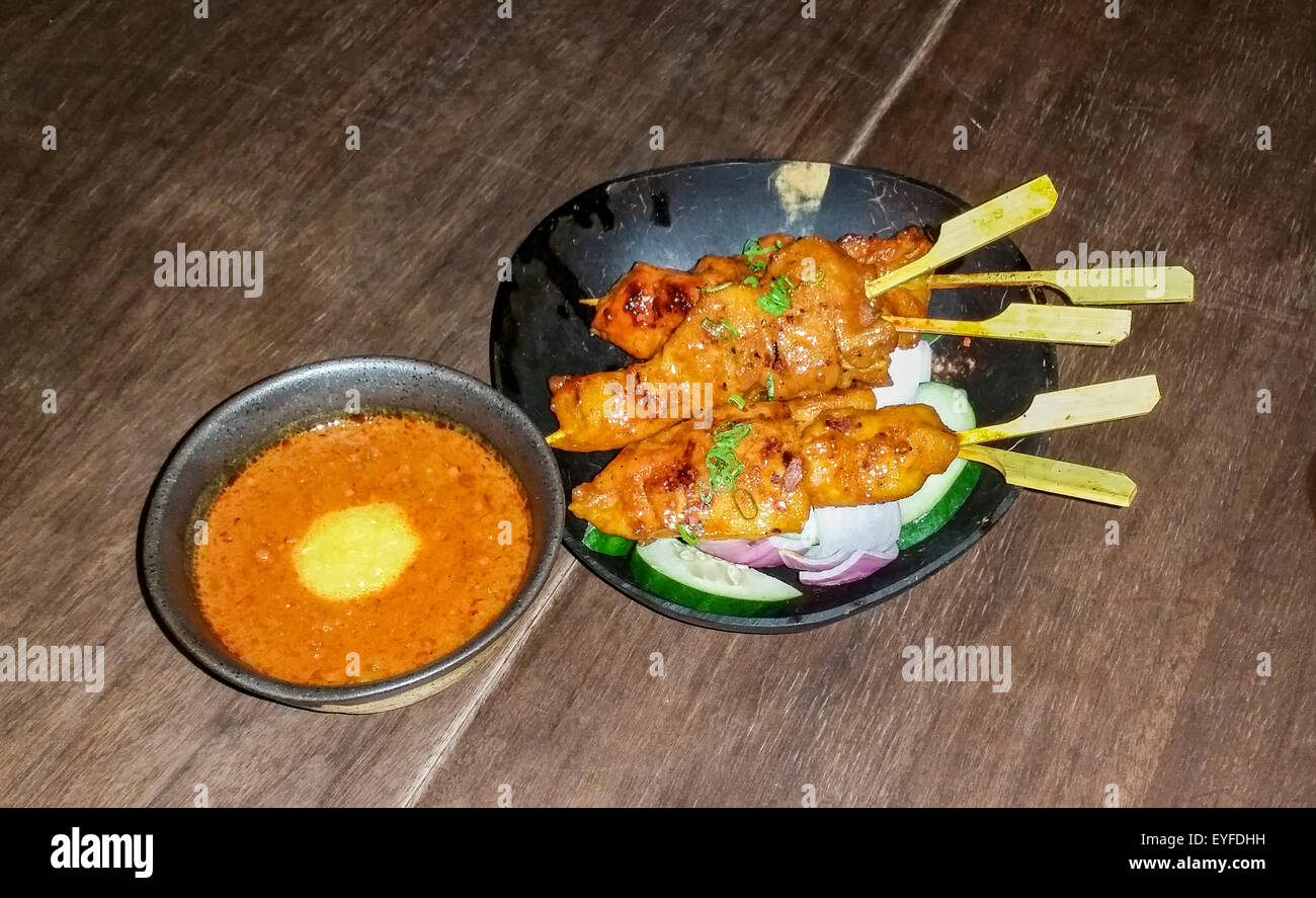 Chicken Satay (Huhn am Spieß) mit Erdnuss-Sauce serviert Kemirinusse, ein Peranakan (eine Mischung aus ethnischen Chinesen/Malaiisch und vieles mehr) Stockfoto