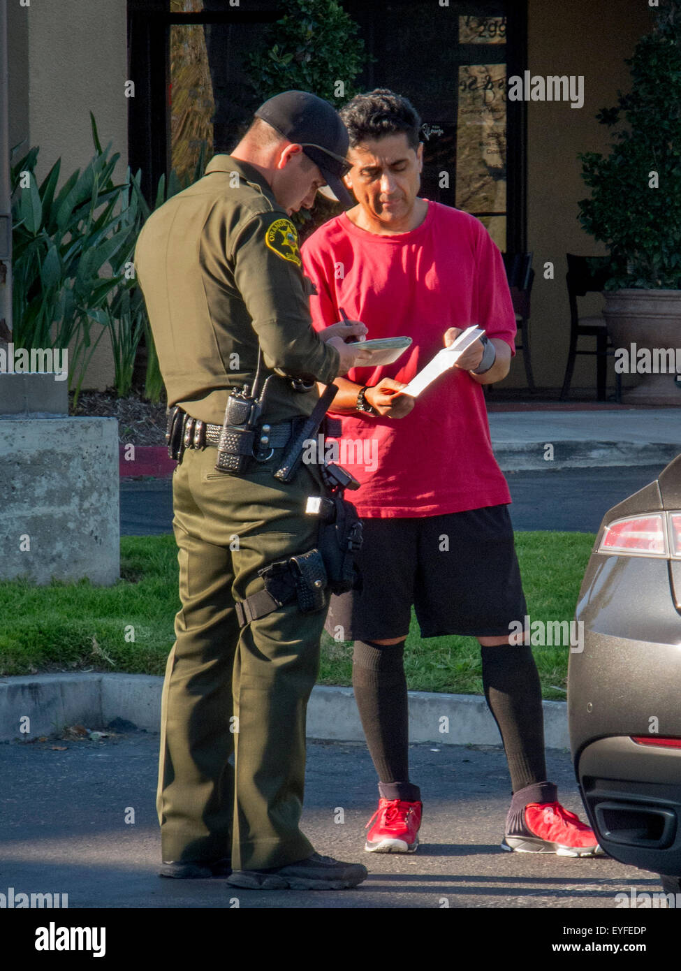 Ein mittleren Alters-Treiber zeigt seine automatische Registrierung, ein Polizist bei einer Verkehrskontrolle in Laguna Niguel, CA. beachten Sie rote Schuhe. Stockfoto