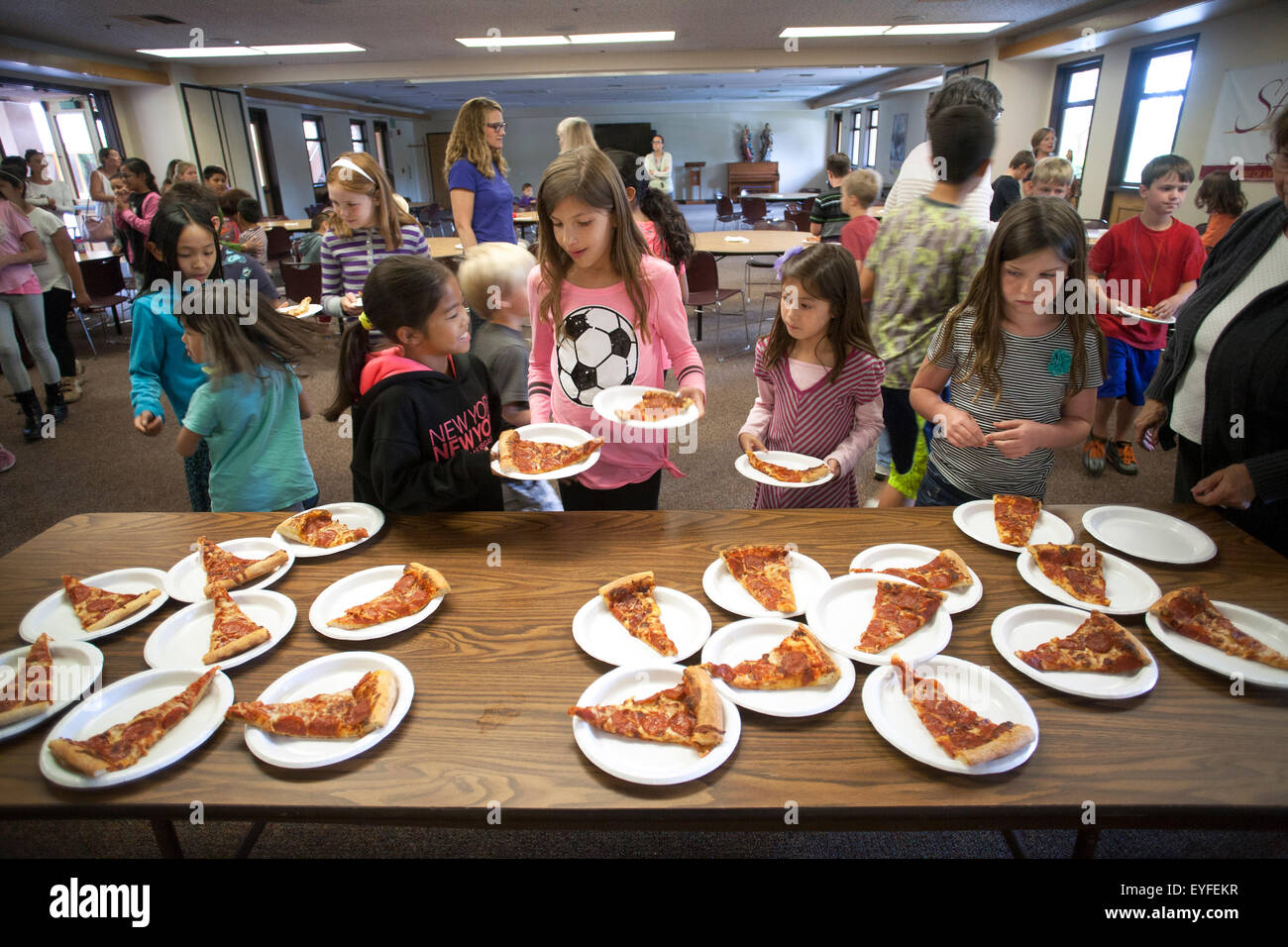 Gemischtrassige Kindern in einer katholischen Kirche Laguna Niguel, CA, genießen Sie Pizza im Gemeindesaal nach einem Kinder-Messe. Stockfoto