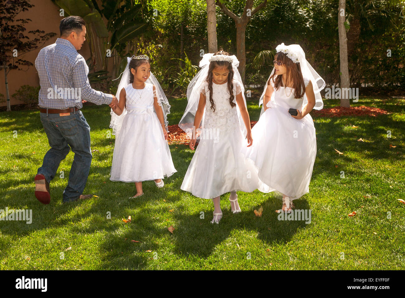 In formalen Outfits, spielen multirassische Mädchen in der Sonne bei einem Laguna Niguel, CA, katholische Kirche vor der Erstkommunion feiern. Erste Heilige Kommunion ist auch bekannt als das Sakrament der Heiligen Eucharistie. Stockfoto