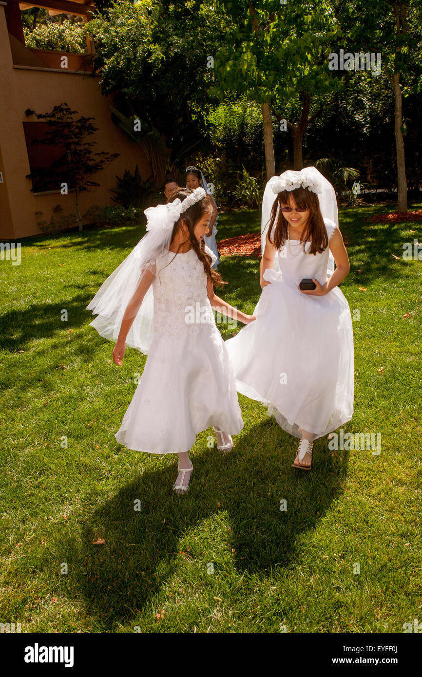 In formalen Outfits, spielen multirassische Mädchen in der Sonne bei einem Laguna Niguel, CA, katholische Kirche vor der Erstkommunion feiern. Erste Heilige Kommunion ist auch bekannt als das Sakrament der Heiligen Eucharistie. Stockfoto