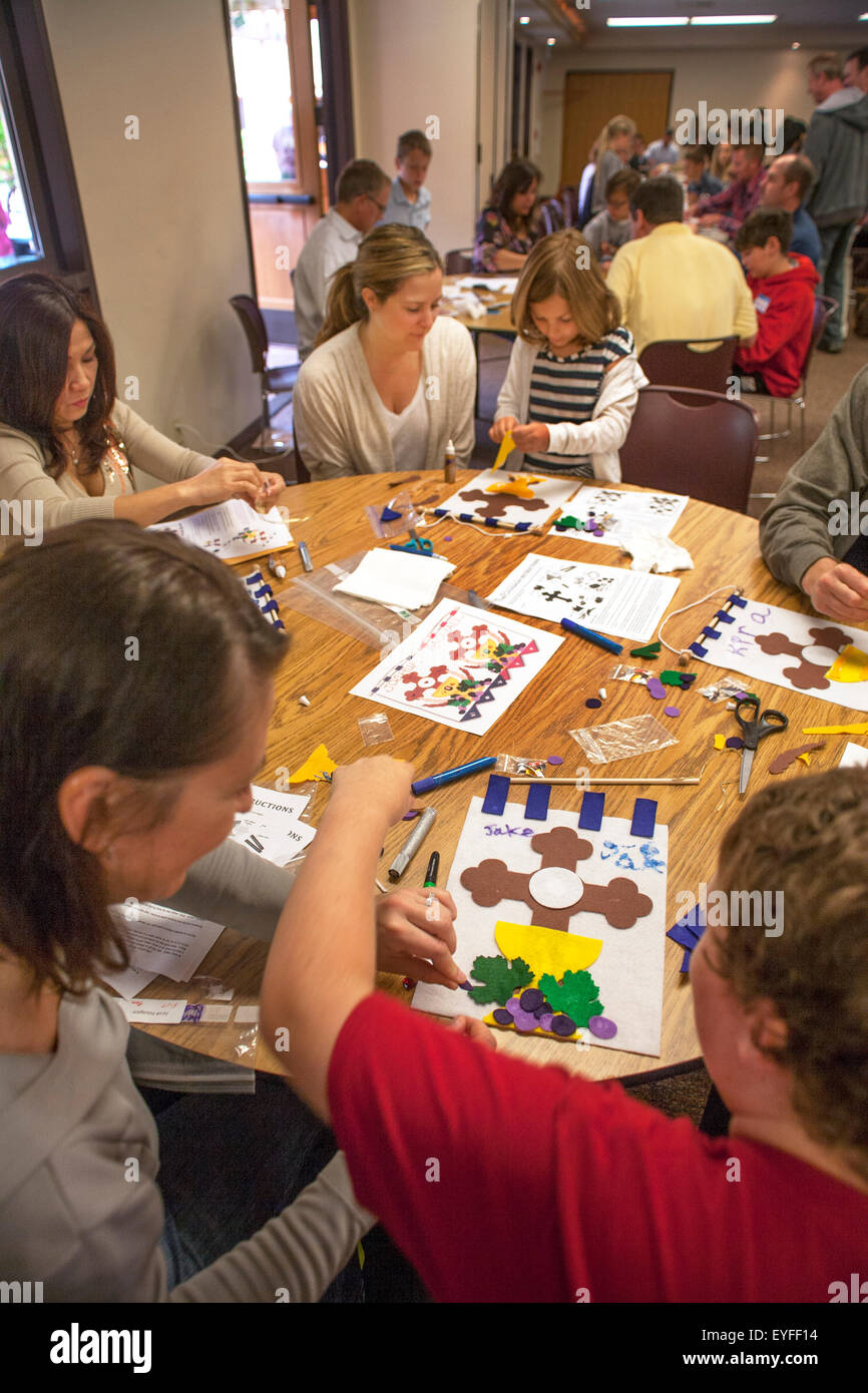 Gemischtrassig Gemeindemitglieder im Gemeindesaal ein Laguna Niguel, CA, katholische Kirche, erste Heilige Eucharistie Banner als Pew Marker für Erstkommunion Zeremonien verwendet werden. Stockfoto