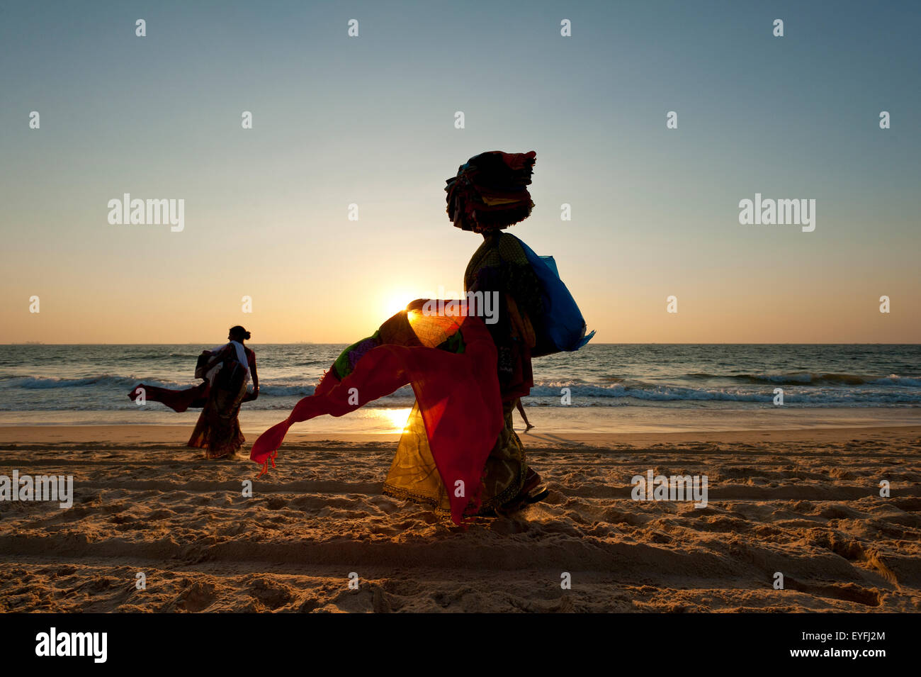 Silhouette einer Frau, die indische Tuch am Strand in der Abenddämmerung zu verkaufen; Candolim, Goa, Indien Stockfoto