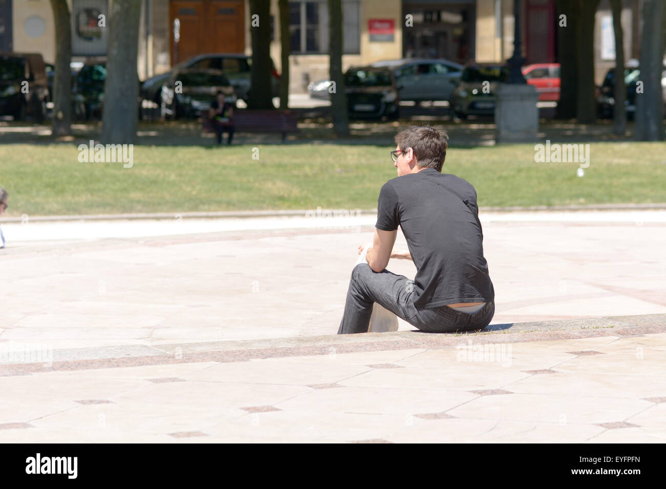 Mann sitzt auf Stufen am Monument Aux Girondins zur Mittagszeit in Bordeaux Frankreich Stockfoto