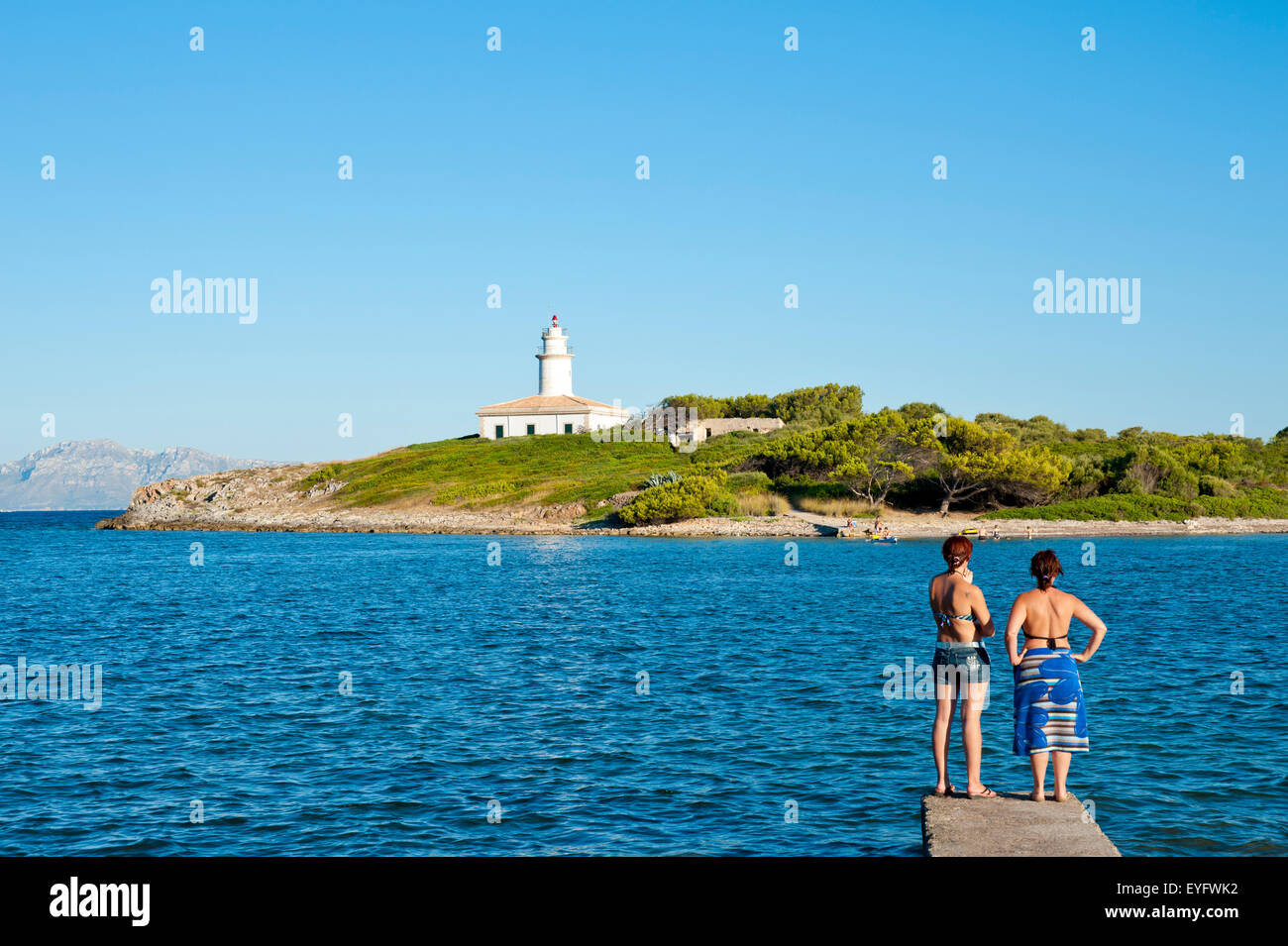 Mädchen genießen den Blick auf die Insel Alcanada und sein Leuchtturm in der Nähe von Alcudia, Mallorca, Balearen, Spanien Stockfoto