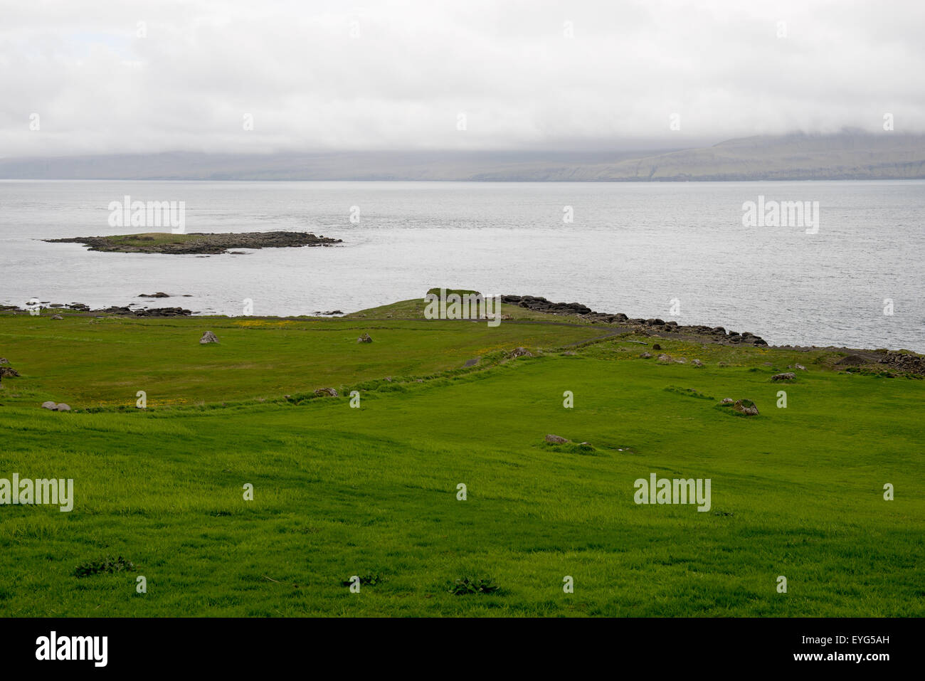 Typische Landschaft auf den Färöer Inseln von Kirkjubour mit grünem Rasen, Berge und Meer gesehen Stockfoto