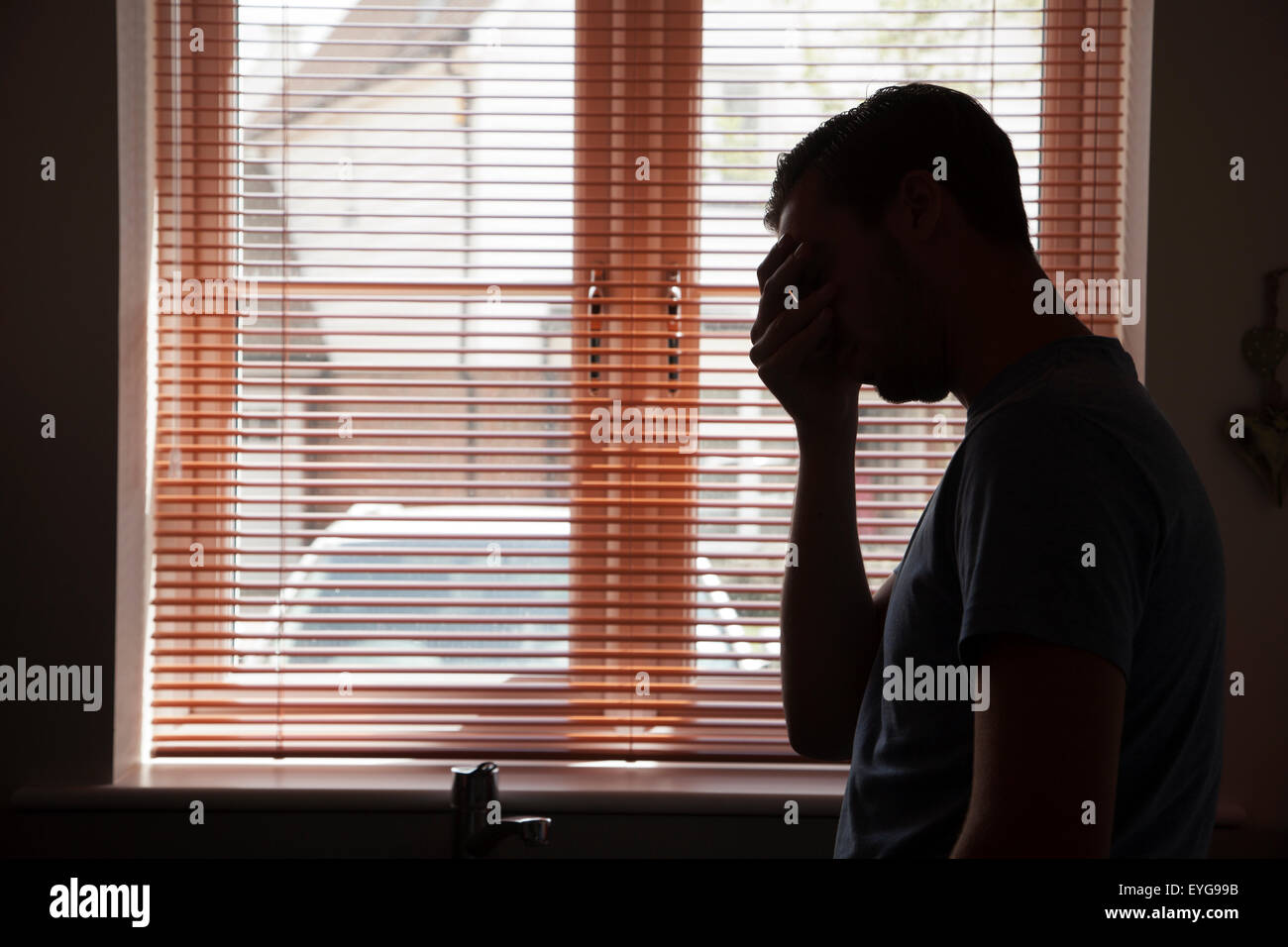Silhouette des jungen Mannes durch ein Fenster. Stockfoto