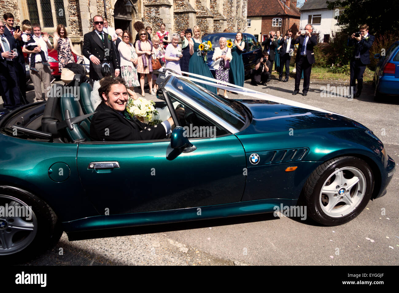 Braut und Bräutigam verlassen Kirche in einem dekorierten BMW Z3 offene Top Sportwagen Stockfoto
