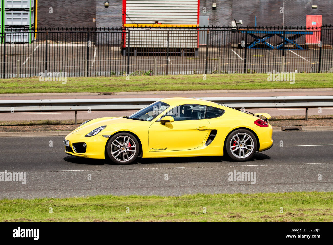 Eine gelbe Porsche 2-Sitzer Coupé Cayman S Sportwagen Reisen entlang der Kingsway West Schnellstraße in Dundee, Großbritannien Stockfoto