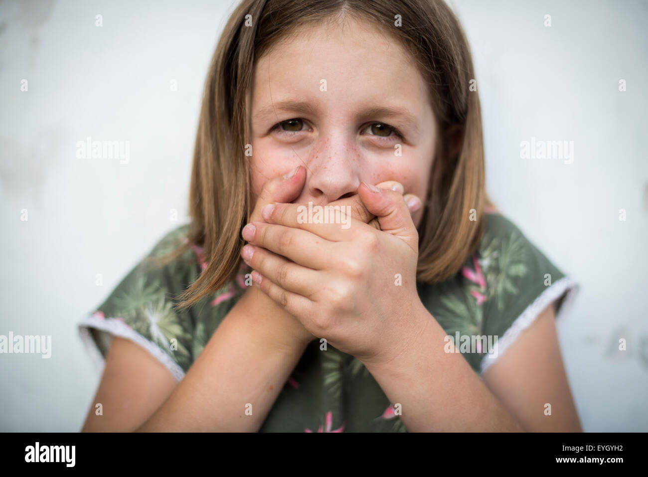 Grundschule Mädchen reichte ihr die Hände vor den Mund Stockfoto