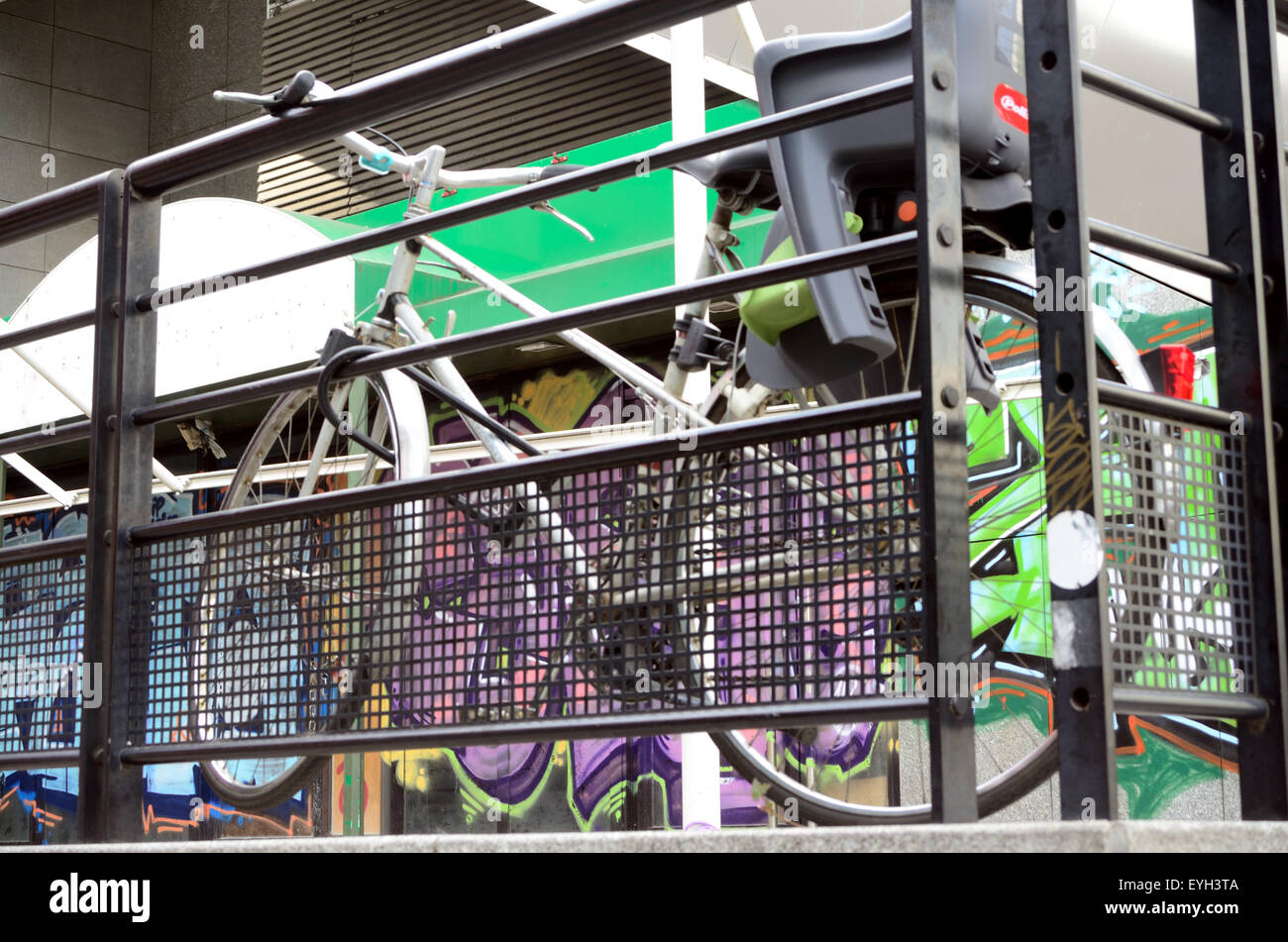 Ein Fahrrad ruht sich gegen einige Geländer. Die Wand hinter ist Graffiti bedeckt. Stockfoto