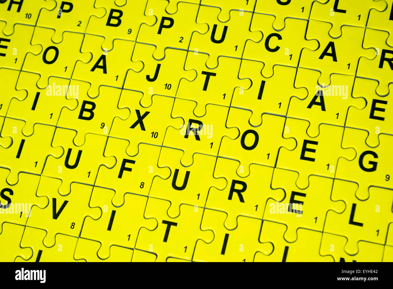 Gelbe Puzzleteile verbunden mit Buchstaben bedruckt auf anderem Hintergrund Stockfoto