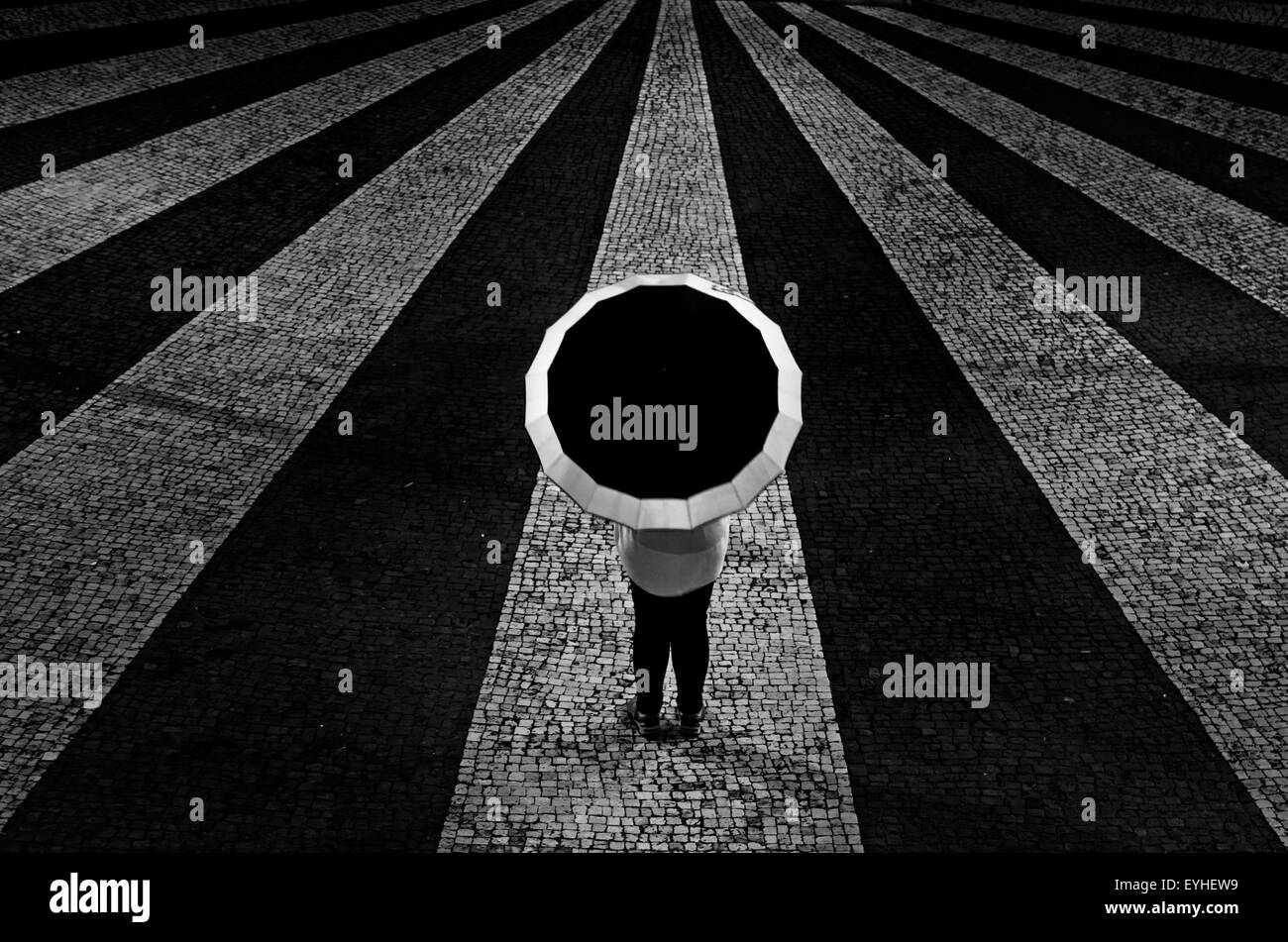 Frau mit Sonnenschirm in der Mitte Streifen schwarz-weiß gepflasterten Platz, alle mit dem Ziel, zu einem Zeitpunkt. Stockfoto