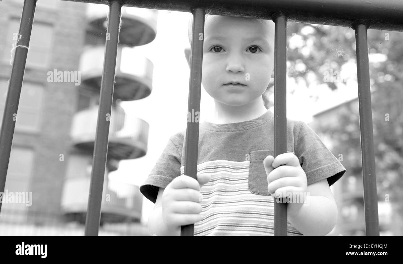 Porträt eines traurigen Kindes hinter Gittern Stockfoto