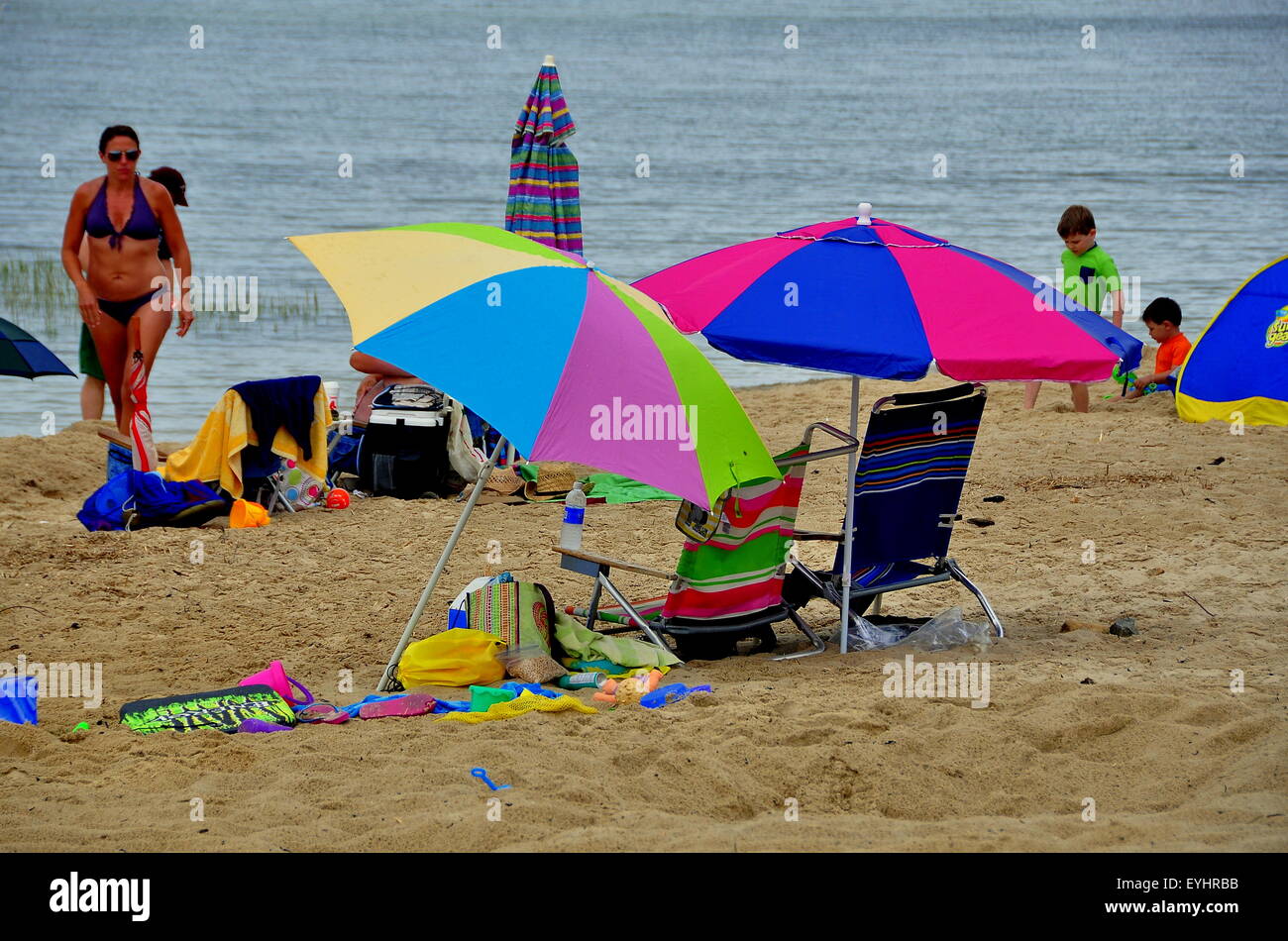 Brewster, MA: Familien genießen einen Sommer am Nachmittag sitzen auf Stühlen im Schatten von bunte Sonnenschirme am Sandstrand Corporation Stockfoto