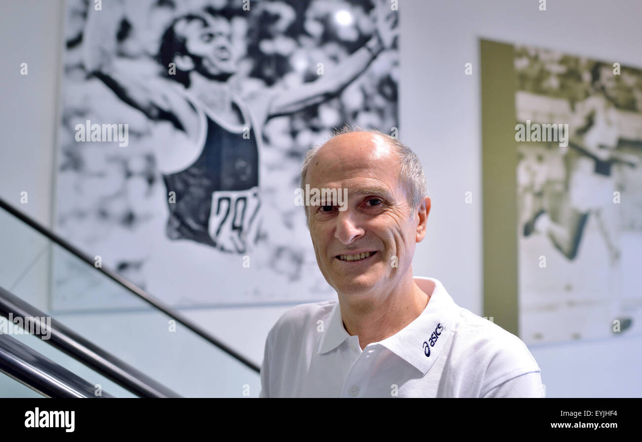 Marathon-Legende Waldemar Cierpinski vor zwei Bilder von ihm über die Ziellinie bei den Olympischen Spielen in seinem Sportgeschäft in Halle/Saale, Deutschland, 28. Juli 2015 posiert. Cierpinski gewann Goldmedaillen bei der Olympiade 1976 in Montreal und vier Jahre später in Moskau. Er wird am 03. August seinen 65. Geburtstag feiern. Foto: Hendrik Schmidt/dpa Stockfoto