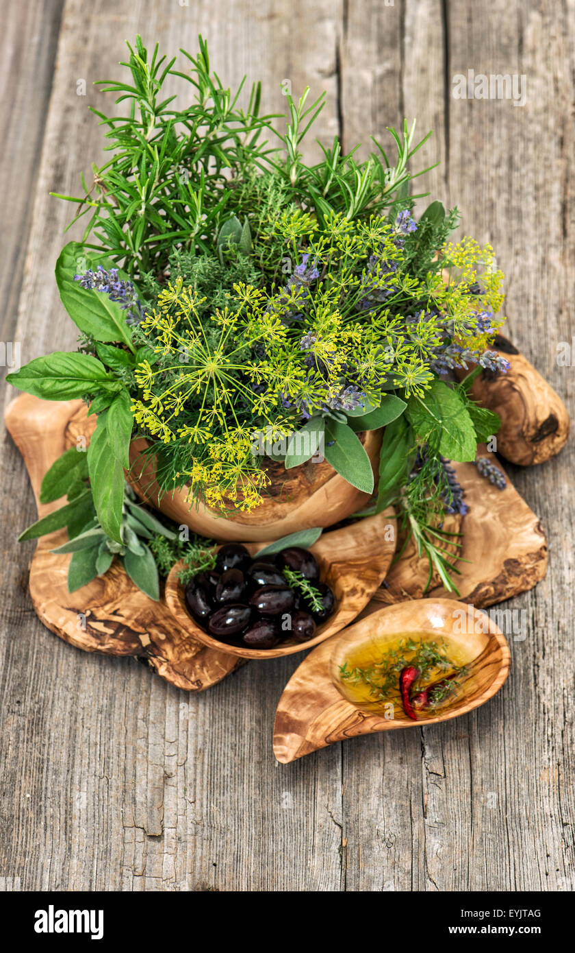 Oliven, Öl, Basilikum, Dill, Salbei, Lavendel, Minze. Kräuter und Gewürze über rustikalen hölzernen Hintergrund. Gesunde Ernährung Stockfoto