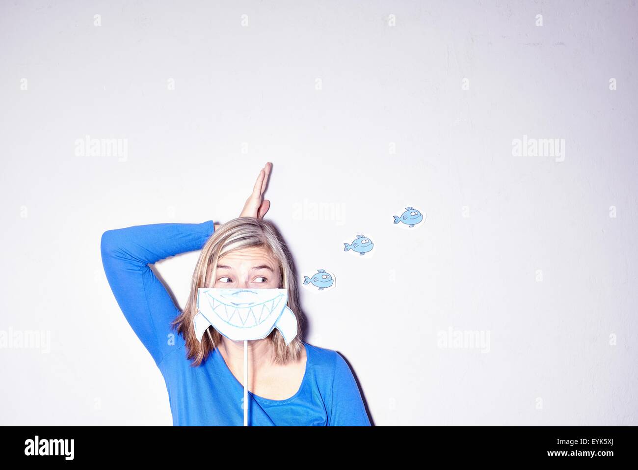 Studioaufnahme von junge Frau mit hand an Kopf hochhalten Zeichnung der Haie Mund Stockfoto