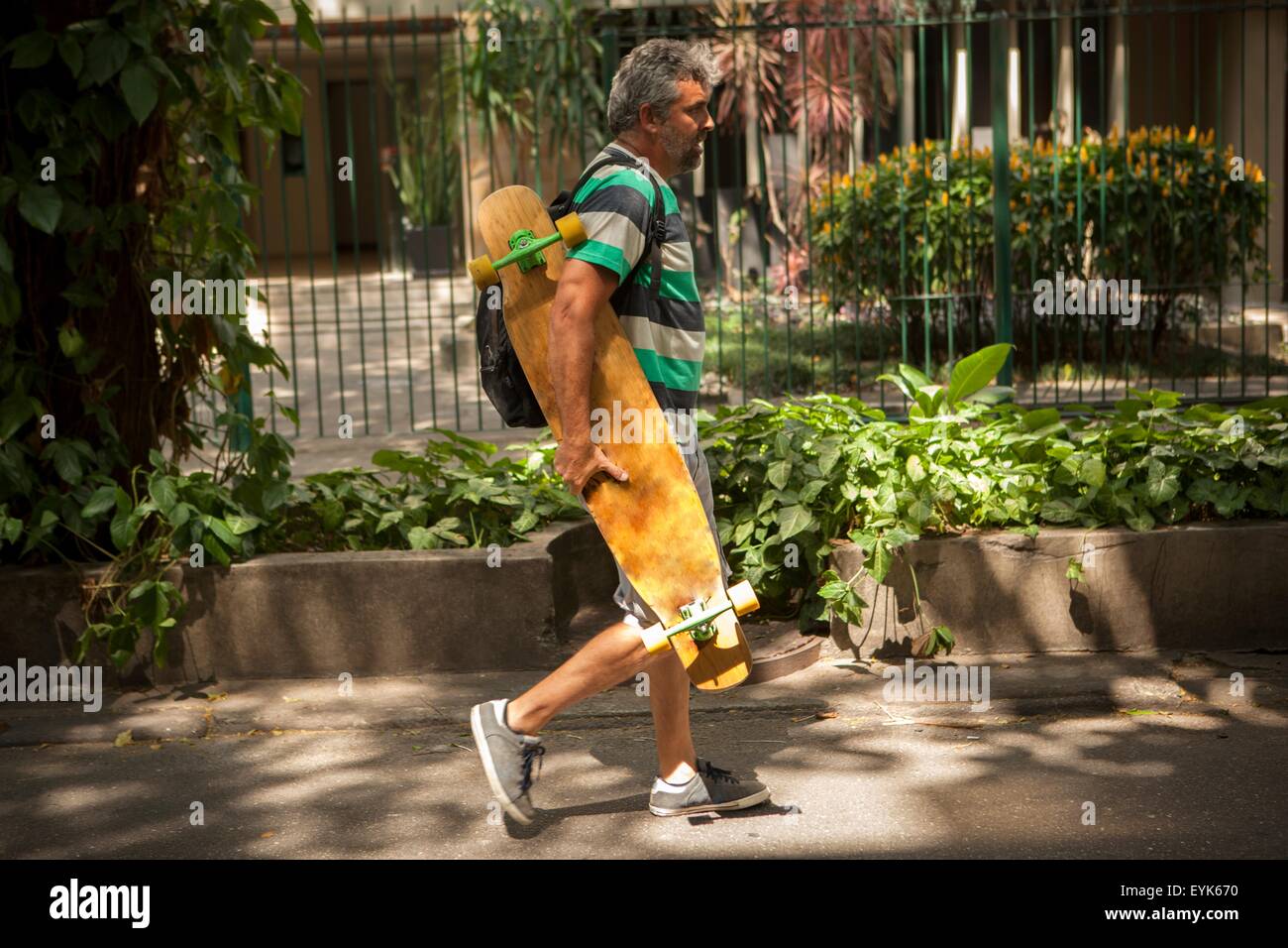 Reifer Mann spazieren am Bürgersteig mit Skateboard, Rio De Janeiro, Brasilien Stockfoto