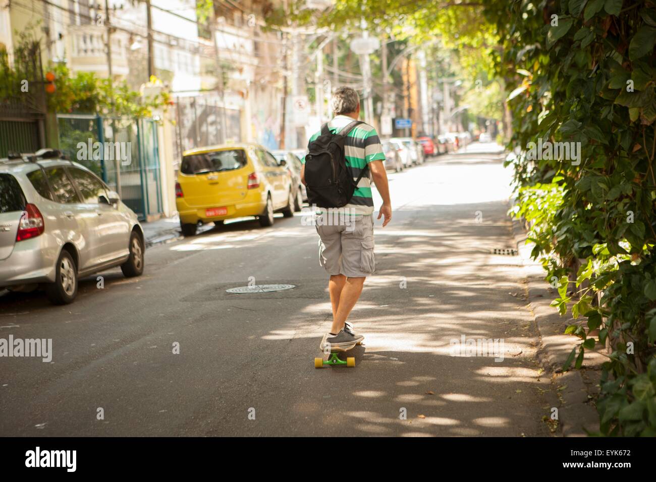 Heckansicht des reifen Mannes Skateboarden auf Straße, Rio De Janeiro, Brasilien Stockfoto