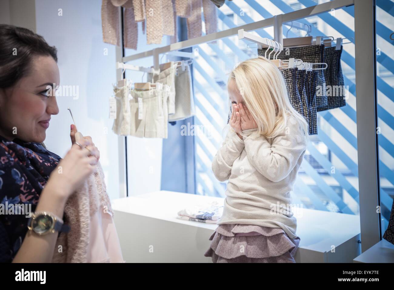 Mutter zeigt Kleid junge Tochter in Kinder-Kleider-shop Stockfoto