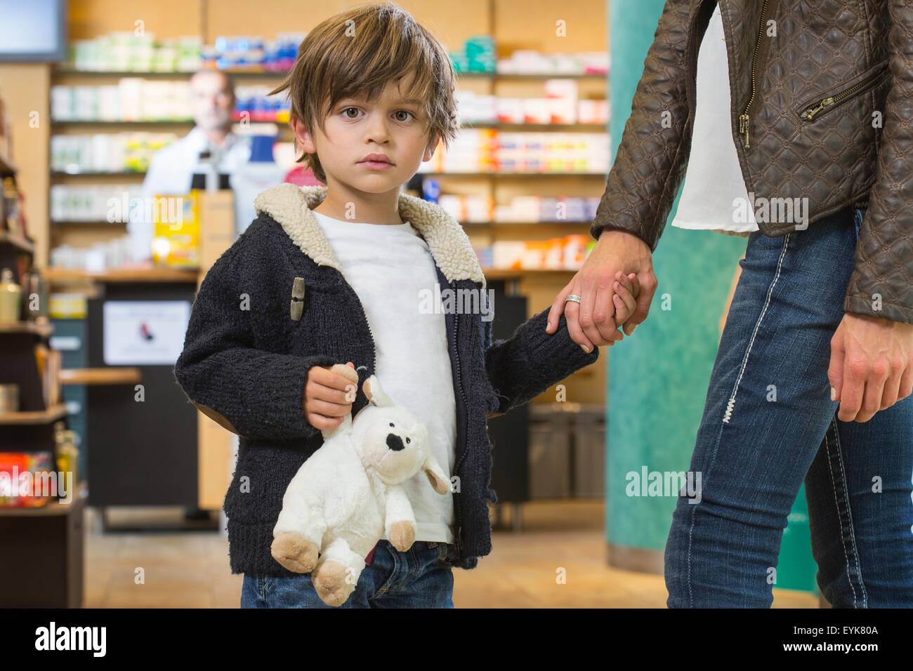 Junge und seine Mutter ist auf der Suche nach medizinischer Behandlung in einer Apotheke Stockfoto