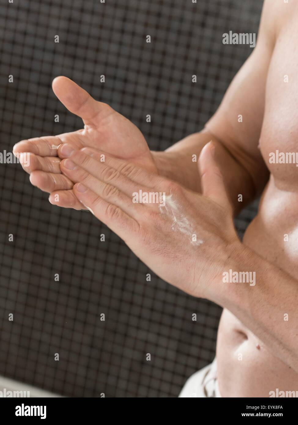 Schuss von muskulösen Mann im Badezimmer in der hand reiben Sahne abgeschnitten Stockfoto