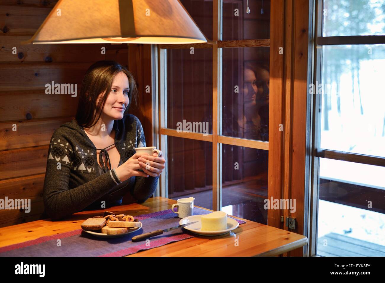 Porträt der jungen Frau Kaffee trinken und der Blick aus dem Fenster, Posio, Lappland, Finnland Stockfoto