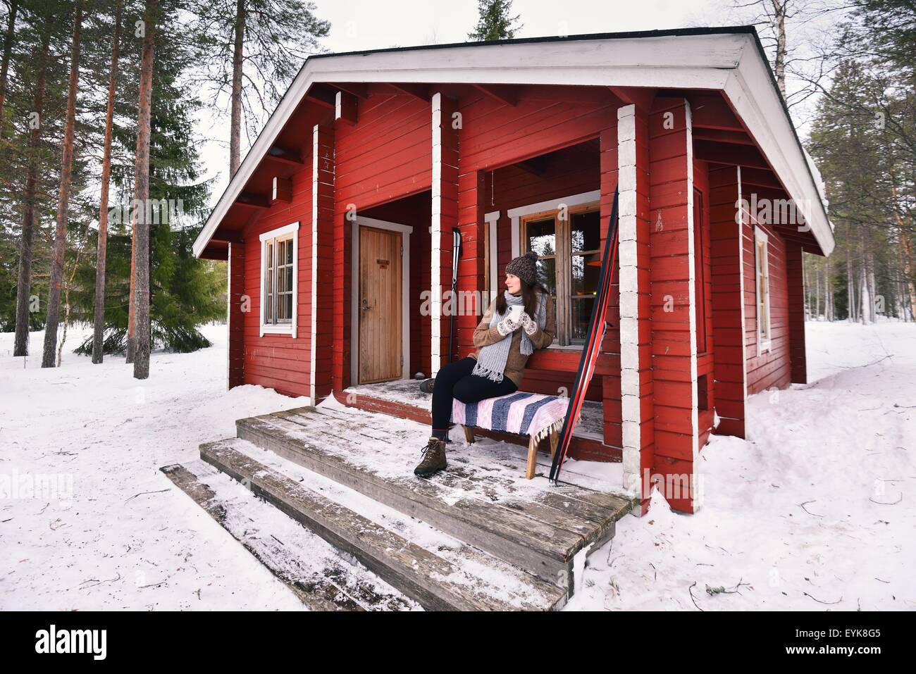 Porträt des jungen Skifahrerin Kaffeetrinken auf Kabine Veranda, Posio, Lappland, Finnland Stockfoto