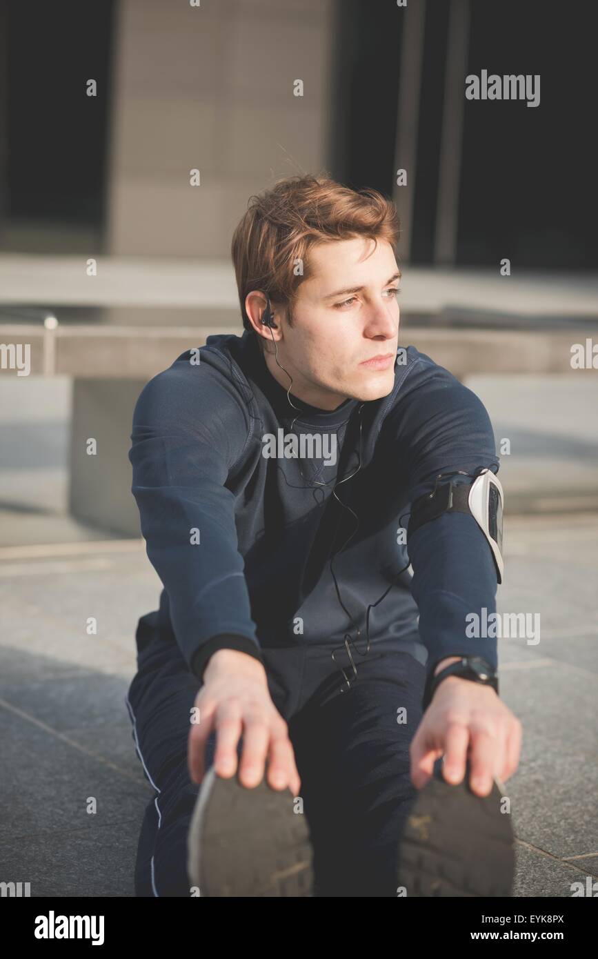 Junge männliche Touch tut Zehen Warm ups in der Stadt Stockfoto