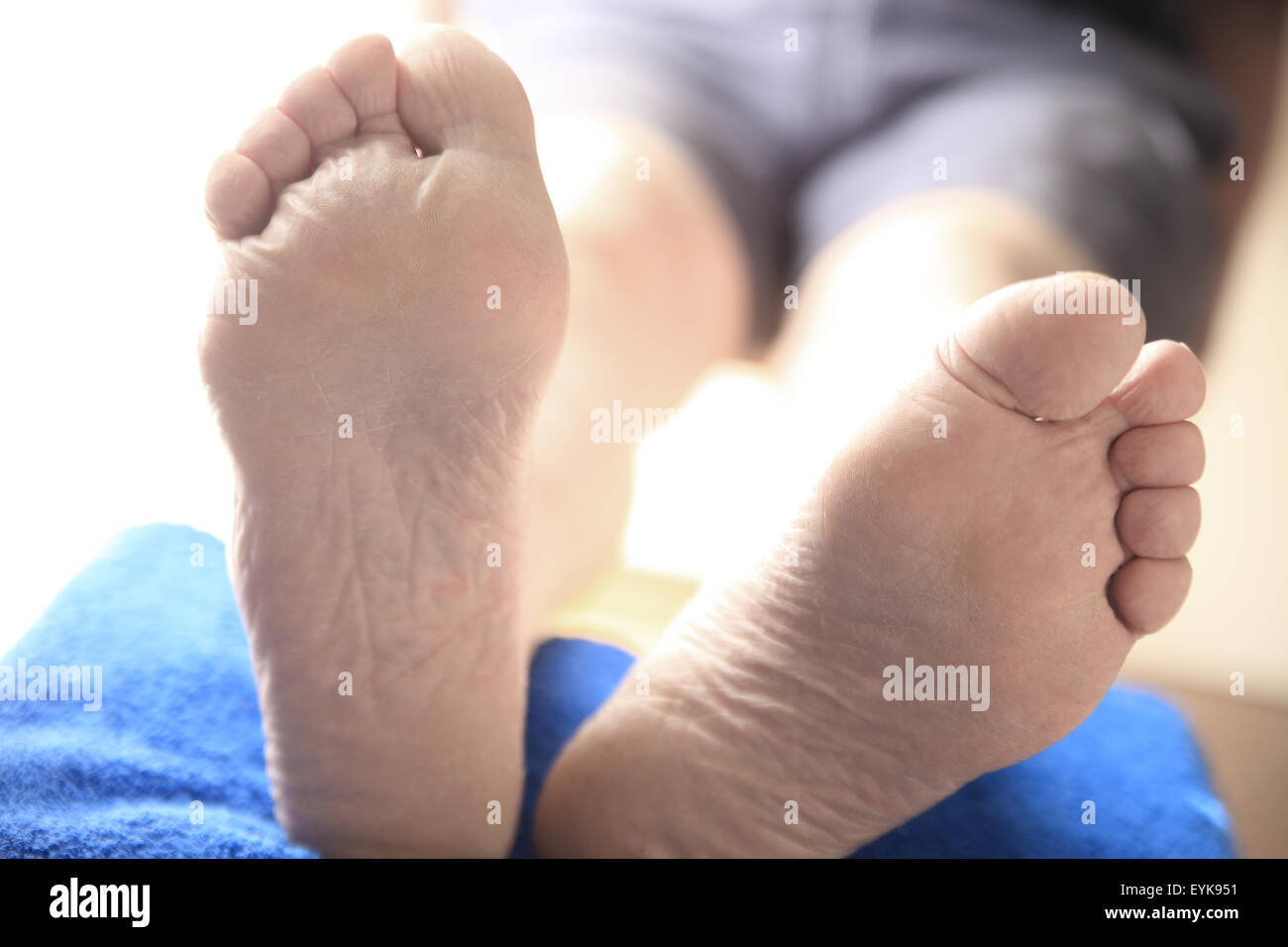 Detailansicht der beiden Füße eines Mannes mit seinen Beinen aufgestützt Stockfoto