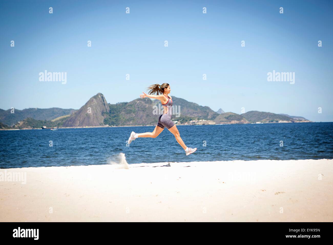 Junge Frau springt auf Strand, Rio De Janeiro, Brasilien Stockfoto