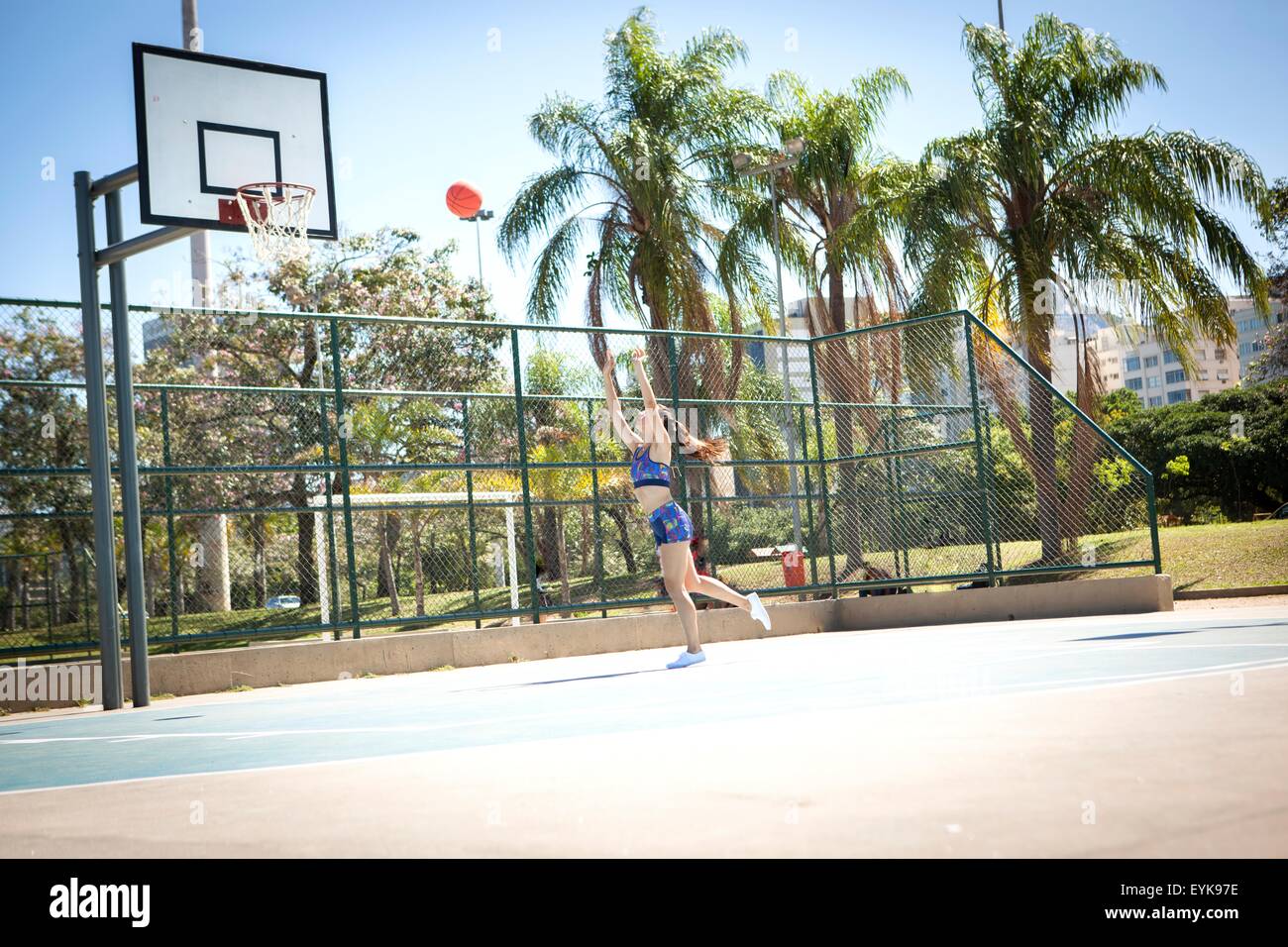 Junge Frau am Basketballfeld im Freien, wirft Ball in Richtung hoop Stockfoto