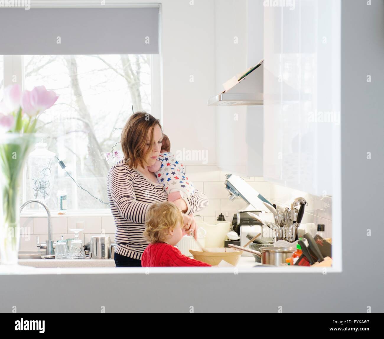 Mutter mit Baby und Kleinkind in Küche Stockfoto