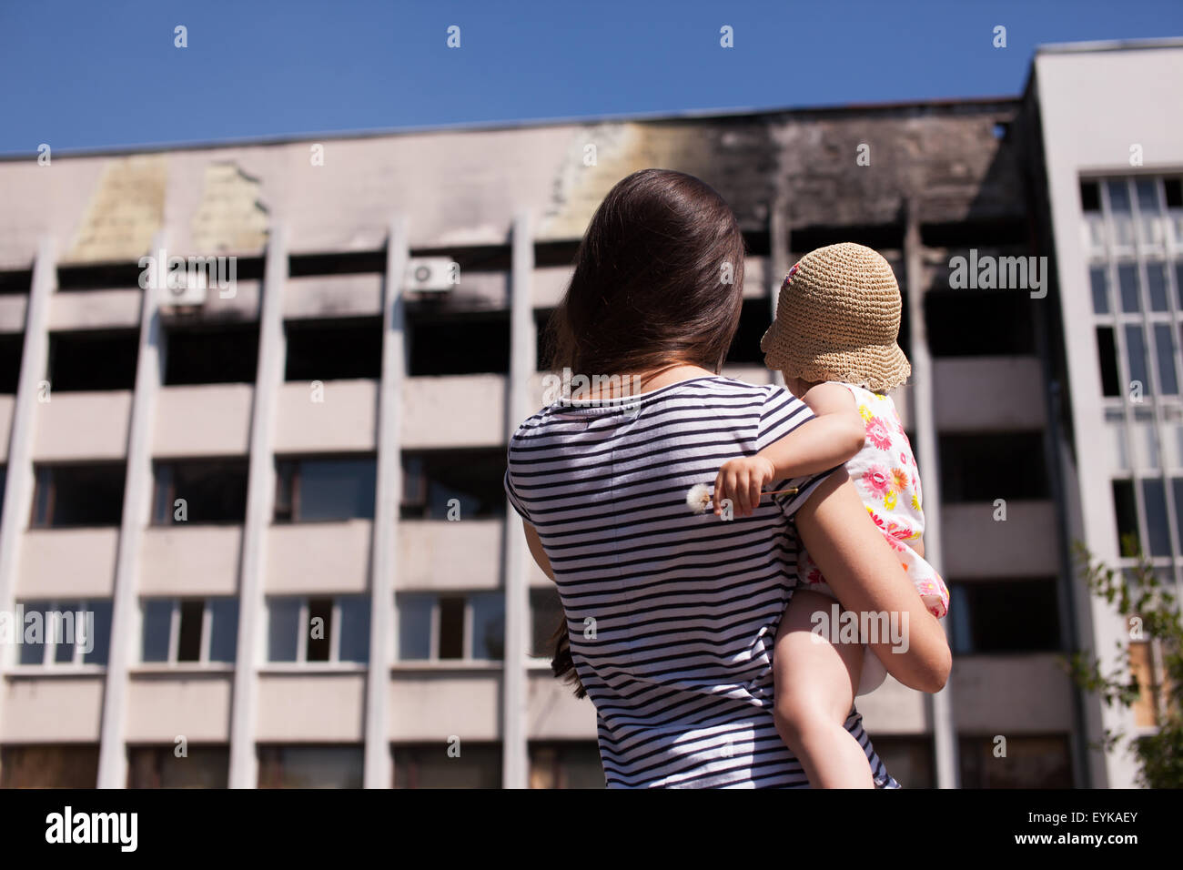 MARIUPOL, UKRAINE - 19. Juli 2015: Mutter mit Baby auf verbrannte Gebäude Mariuopl Rathaus Stockfoto