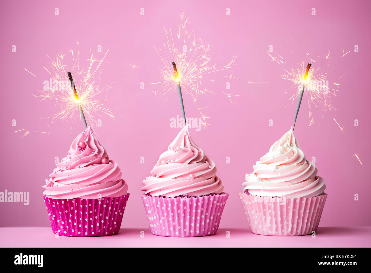 Drei Muffins mit rosa Zuckerguss und Wunderkerzen Stockfotografie - Alamy