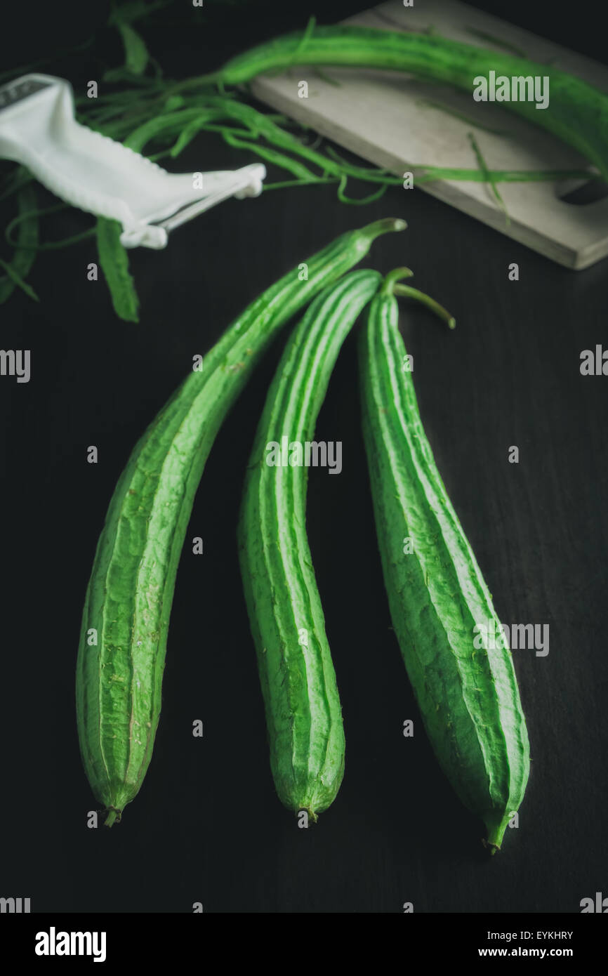 Winkel-Kürbis oder abgewinkelt Luffa Schwamm Kürbis mit mystischen Licht auf schwarzem Holz Hintergrund Stockfoto