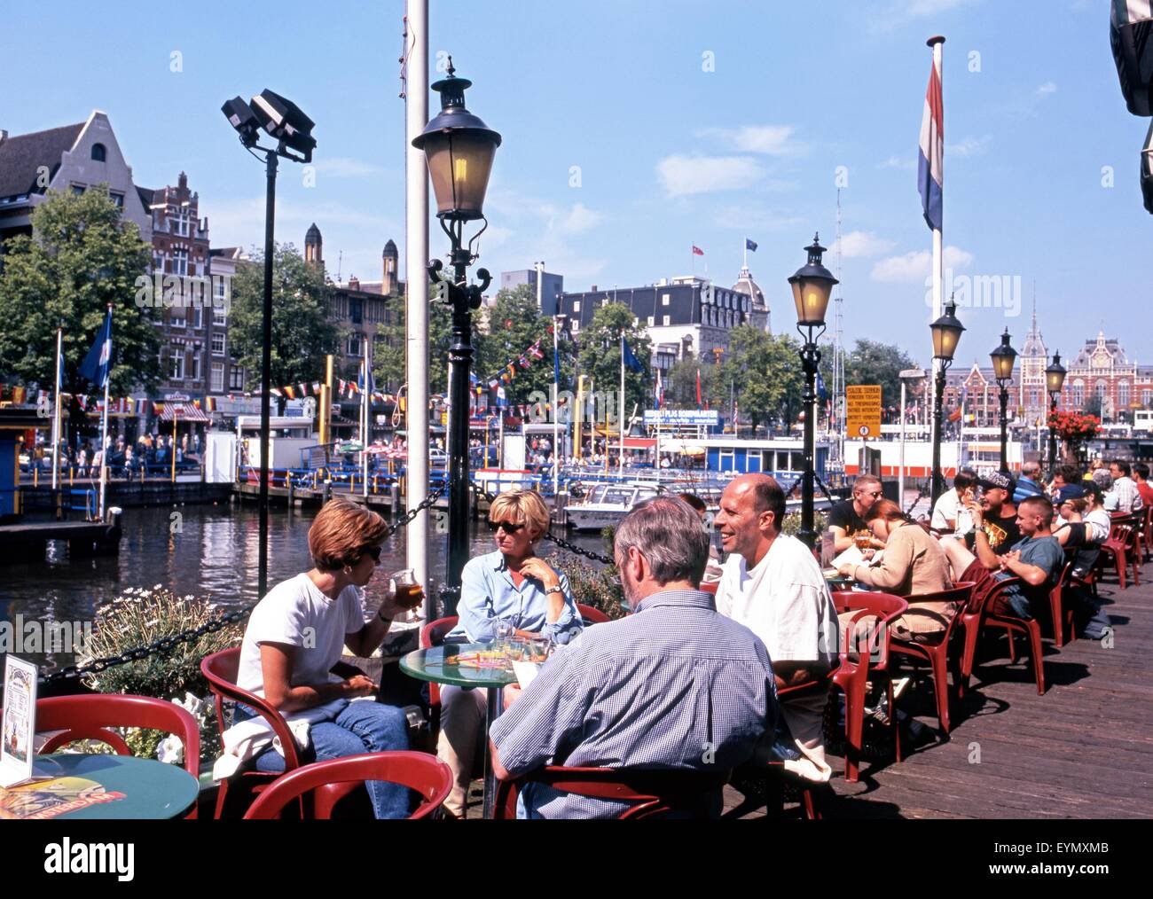 Menschen entspannen in einem Straßencafé entlang Damrak, Amsterdam, Holland, Niederlande, Europa. Stockfoto
