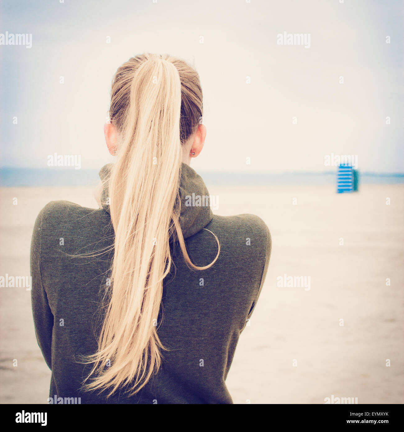 Einsames Mädchen mit langen blonden Pferdeschwanz am leeren Strand von neblig. Selektiven Fokus. Bild mit Filterwirkung Stockfoto