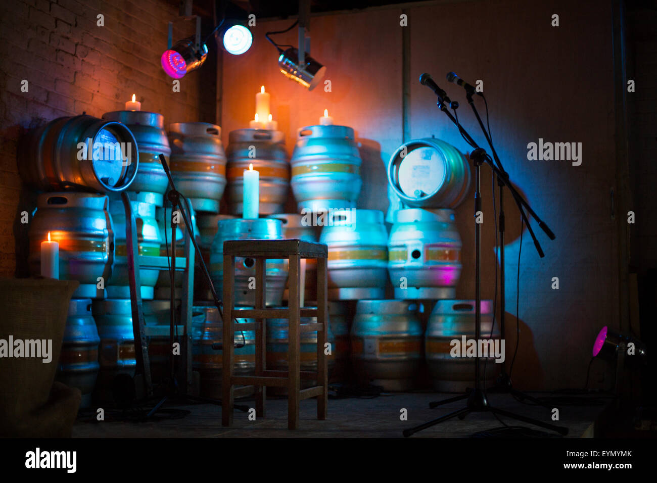 Kleine intime, leere Bühne mit verschiedenen farbigen Lichtern mit Bierfässern, Kerzen und Hocker. Stockfoto