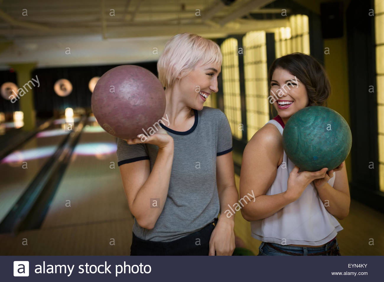 Lächelnde junge Frauen halten Bowlingkugeln Stockfoto