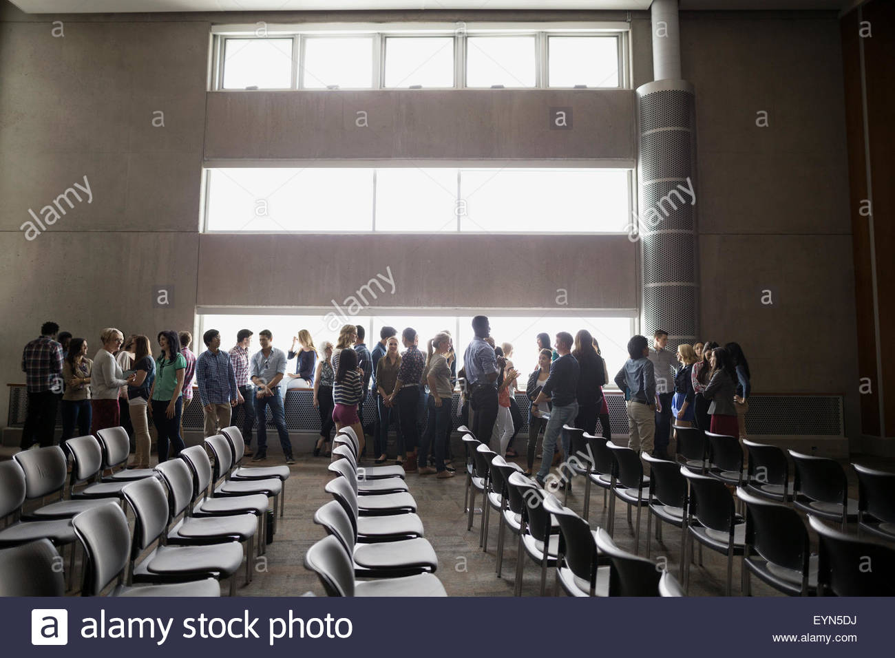 Studenten, die Geselligkeit entlang Windows im auditorium Stockfoto