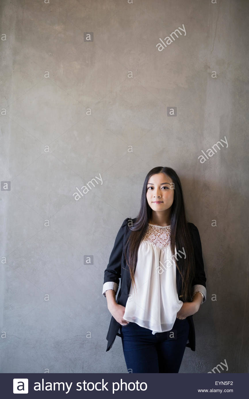 Selbstbewusste Frau Porträt Hände in den Taschen grauen Hintergrund Stockfoto